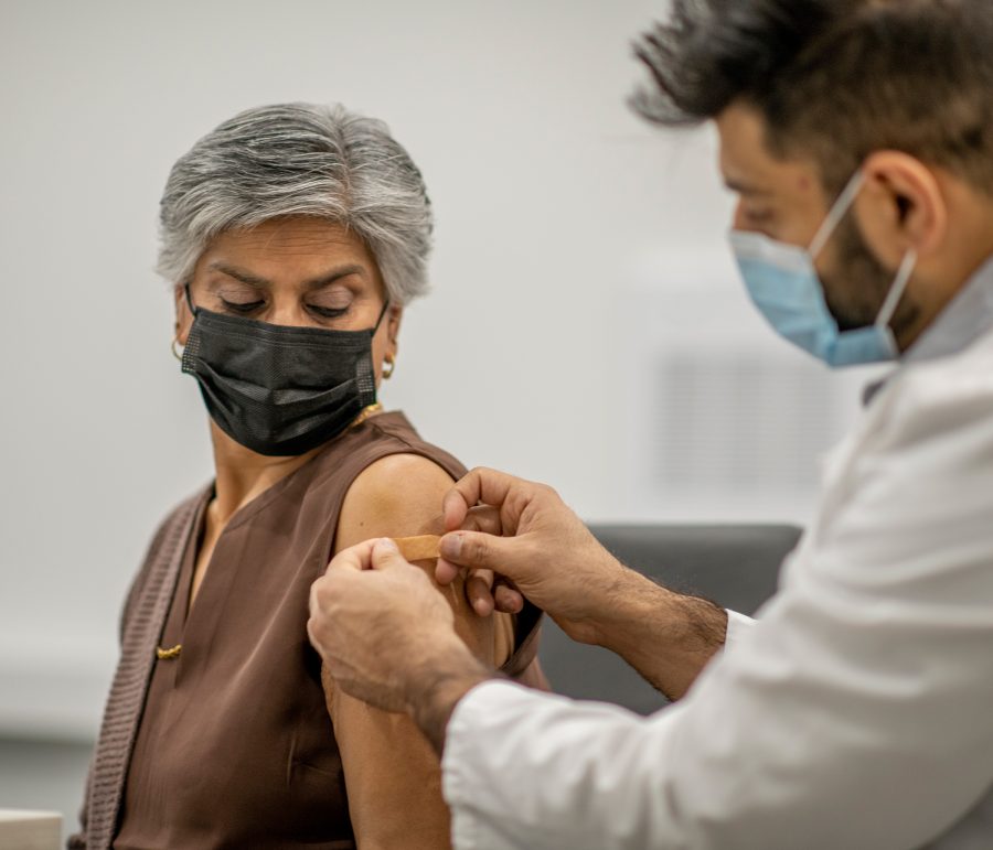 Older woman receiving a vaccination from a physician