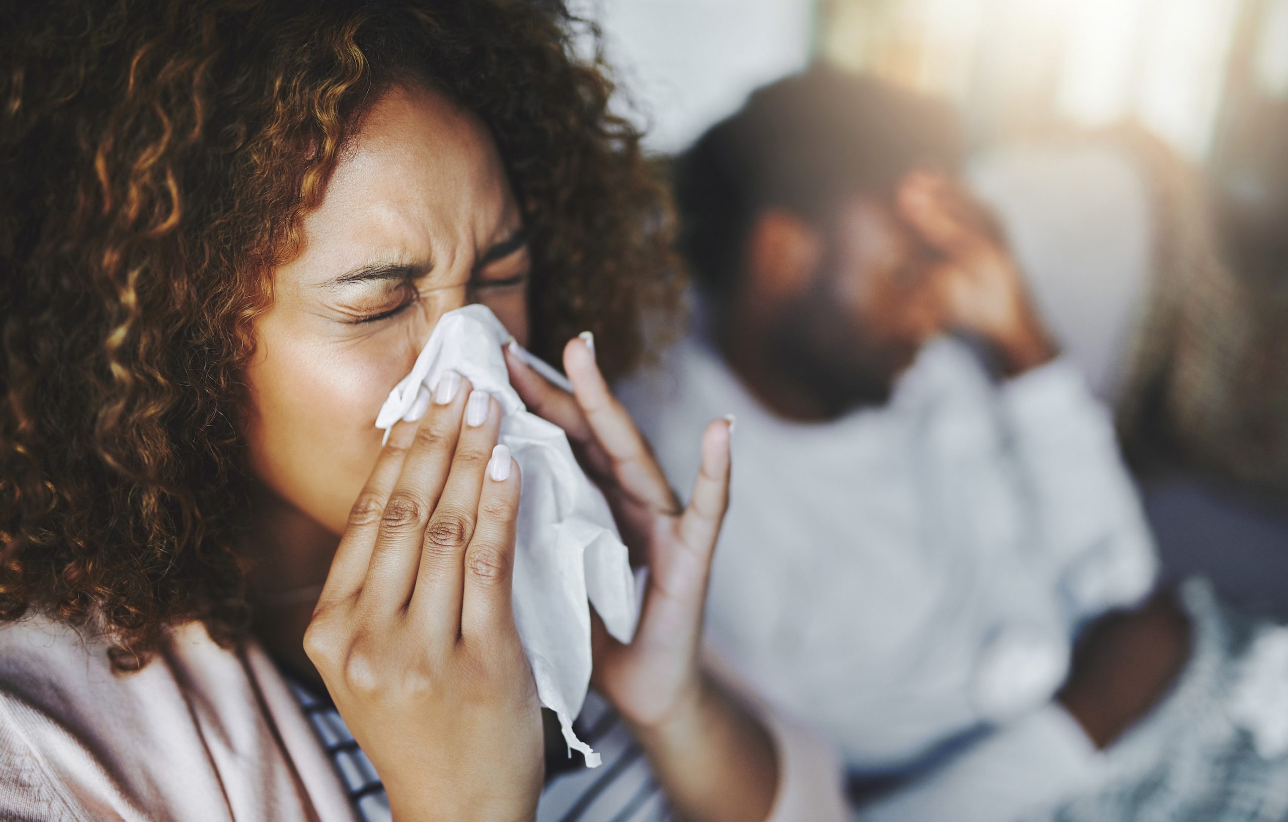 A woman blows her nose into a tissue.