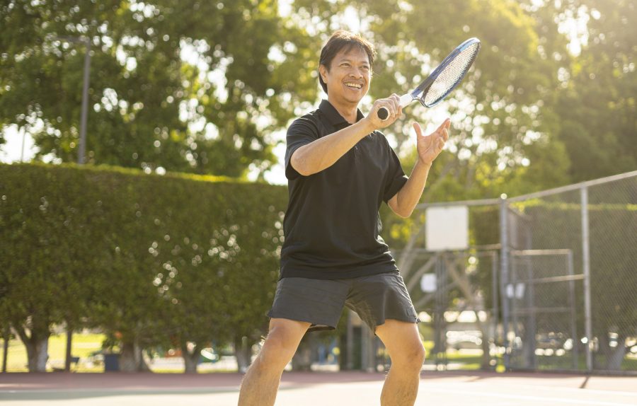 Mature man playing tennis hitting the ball closeup
